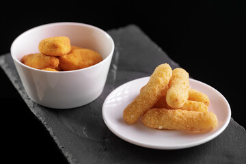 Crispy chicken nuggets and cheese sticks on slate background, top view