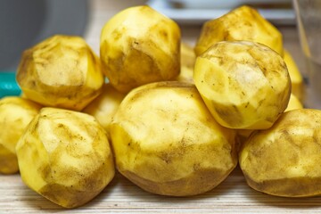Peeled but unwashed potatoes lying on a kitchen table before cooking