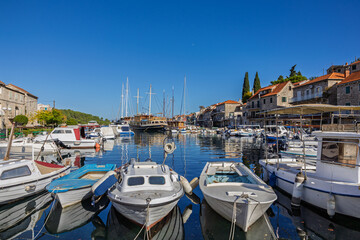Obraz premium Coastal Harbor Village With Stone Buildings, Boats, And Calm Blue Water Reflections