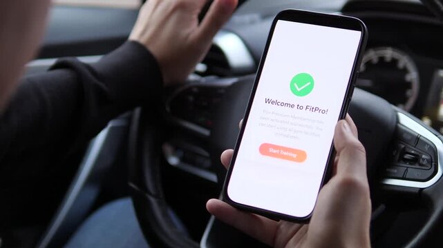 A man uses his phone in a parked car to read and sign up for a gym membership, culminating in a successful confirmation. This clip captures the decisive moment of committing to a healthier lifestyle.