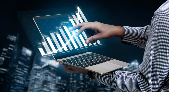 A businessman interacts with digital data visualization on a laptop while overlooking a city skyline at night, representing modern business analysis. Impute
