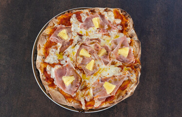 Hawaiian pizza with ham and pineapple on metal tray