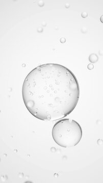 Macro of three drops of transparent liquid merge into one with bubbles inside on white backdrop. Skin care serum droplets uniting into one. Cosmetics moisturizer fluid concept Vertical video