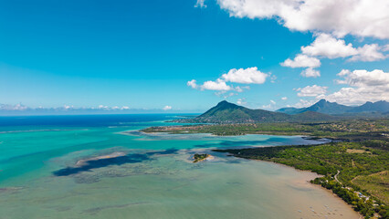 Panoramic aerial view of tropical coastline with turquoise lagoon waters distinctive mountain peaks and lush green vegetation landscape scenery