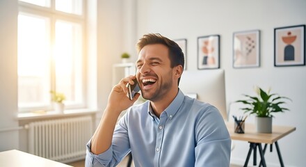 Man in blue shirt laughing while talking on a smartphone in a bright modern office setting at his desk