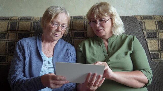 Mother and daughter exploring digital tablet together. Intimate domestic moment with shared tech activity. Mother and daughter engaging with tablet. Foster trust and family connection