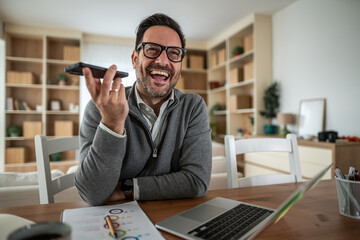 Man laughing talking on speakerphone during home work