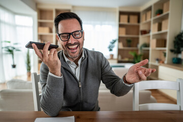 Man laughing talking on speakerphone during phone call at home