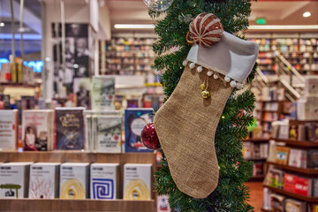 Christmas stocking decoration hanging in a mall bookstore with blurred bookshelves with festive ambiance and copy space for seasonal promotions and holiday-themed designs
