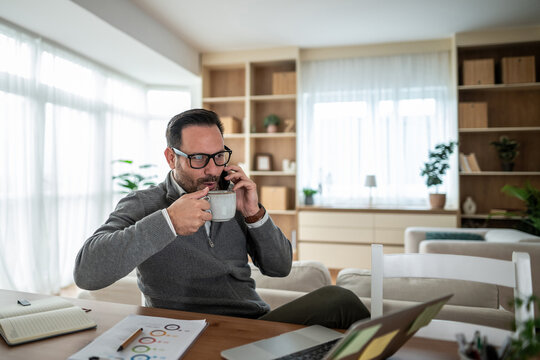 Man working remotely, talking on phone, drinking coffee