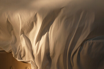 Bed linens in warm sunset light, backdrop for text and ads. Changing bed sheets on a king size bed