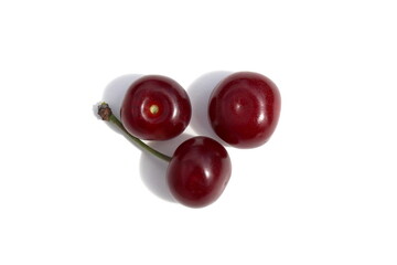 There are three ripe cherries on a white background.