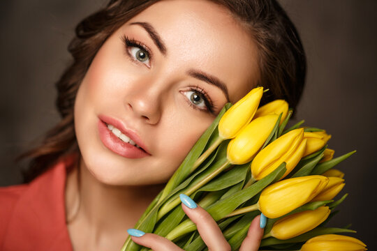 A young woman with striking blue eyes holds a bouquet of yellow tulips, conveying a feeling of serenity and thoughtful reflection. The upward gaze suggests introspection and peaceful contemplation. - Powered by Adobe