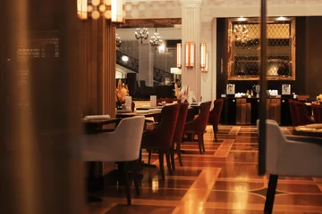 Fototapete Hotel Chic An elegant luxury restaurant dining room interior with plush red and white chairs, warm lighting, and glossy wood flooring.  © Kyrylo