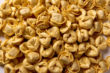 Sfondo di cappelletti freschi, tipica pasta ripiena di carne della cucina emiliano - romagnola,...