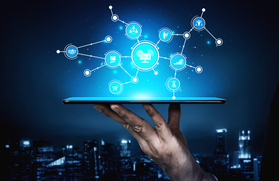 A person holds a tablet displaying glowing digital connections and icons, symbolizing technology and communication in a modern cityscape at night. Tessel