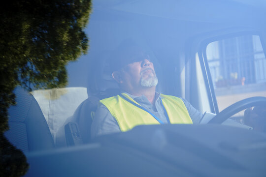 Delivery man sleeping in truck cab taking break