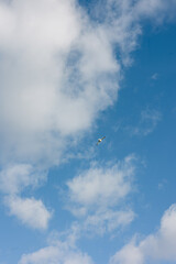 Small aircraft flying high in the sky with fluffy clouds on a sunny day