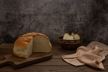 Homemade wheat bread lies on a cutting board on a wooden table. Food.