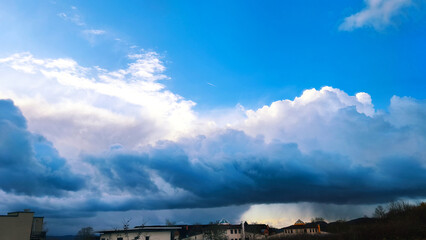 Dramatic sky with dark storm clouds and a bright blue sky above the horizon