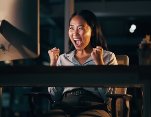 Obraz premium Joyful woman celebrating success at desk with bright computer screen
