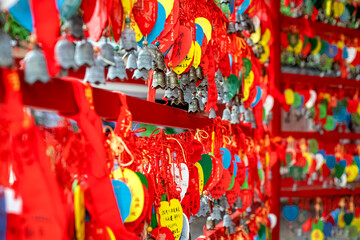 Carved bronze bells and red ribbons with Chinese characters at a temple.