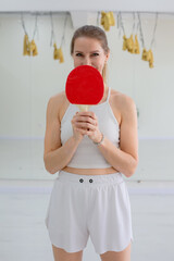 Smiling Woman Holding a Red Table Tennis Paddle