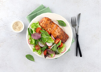 Grilled salmon fillet with fresh vegetable salad on a white background. Healthy food. Top view.