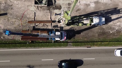 Aerial view of road construction repair site with working cranes next to moving railway system on a sunny day