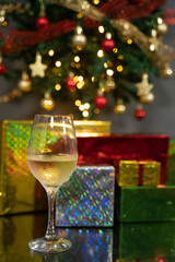 Close-up of a glass od water Christmas Start holding, with a glowing Christmas tree and star topper softly blurred in the background.