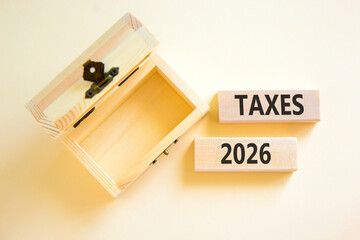 Taxes 2026 new year symbol. Concept words Taxes 2026 on beautiful wooden blocks. Beautiful white paper background. Beautiful empty wooden chest. Business and taxes 2026 new year concept. Copy space.