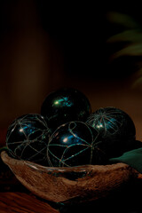 deep emerald christmas ornaments in a textured glass bowl with warm dramatic festive lighting