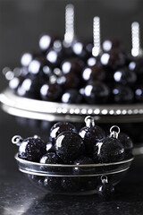 Black glitter christmas ornaments in clear glass bowls with modern reflective holiday lighting