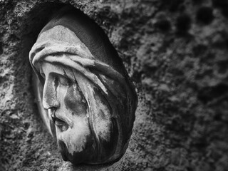 Profile detail of a stone relief depicting Christ, captured in dramatic black and white.
