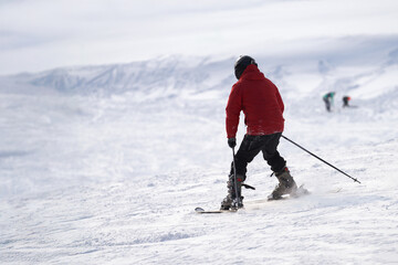 A skier skis down a snowy slope at a ski resort.
