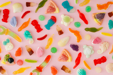Creative pattern made of gummy candies on pastel pink background. Minimal trendy gummies concept. Jelly sweets aesthetic. Colorful flat lay background image. Top view.