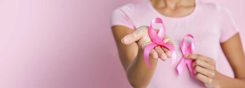 Wide banner with woman holding pink ribbon, breast cancer awareness on pink background, female health symbol, copy space for medical campaign design - Powered by Adobe