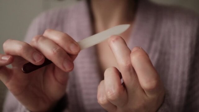 Taking care of nails at home. Home manicure. Woman saves money on beauty procedures. Hans spa treatment at home. Using nail file for nails.