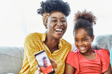 Portrait of mother and daughter having fun with a smart phone at home, family life, parenting, love and bonding concepts