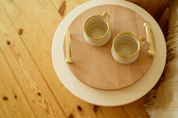 Two white cups on a wooden round table
