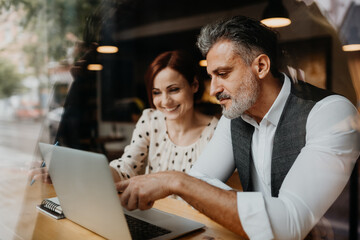 Two coworkers in modern office, talking about project.