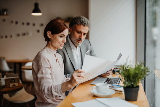 Woman showing project to client during business meeting in a coffee shop.