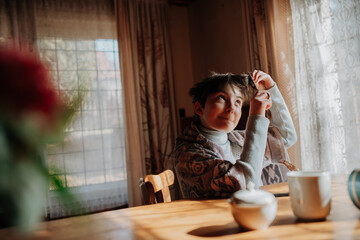 Young girl cutting her hair at home due to financial hardship.