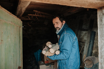 Despaired man carrying firewood for heating at home.