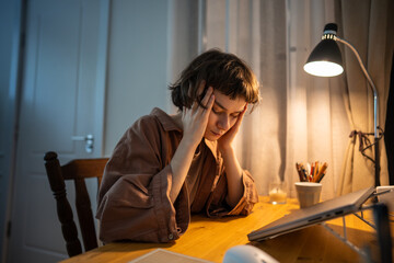 Obraz na płótnie Canvas Exhausted female worker press fingers to forehead battling stress after late home shift. Headache fatigue, remote work stress, mental exhaustion, young woman burnout, temple massage, night strain