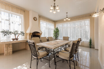 A spacious dining area features a long table surrounded by chairs, with large windows allowing natural light and a fireplace enhancing the inviting atmosphere