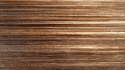 Fototapeta premium Close-up of a stacked, textured metallic surface with horizontal lines, displaying a warm bronze or copper sheen and varied light reflections.