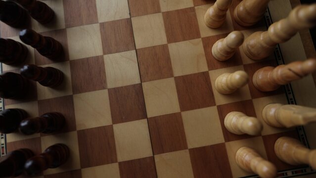 Dynamic video sequence of chess pieces positioned on a slowly rotating chessboard, symbolizing the intellectual confrontation between black and white opposing forces in strategic gameplay. Top view
