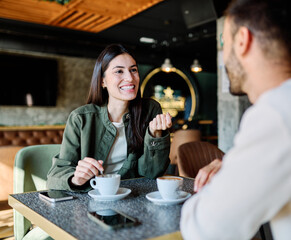 Young couple enjoying conversation and coffee together at an urban cafe table