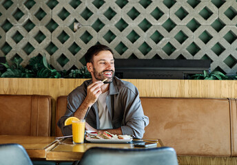 Young man enjoying eating lunch at restaurant